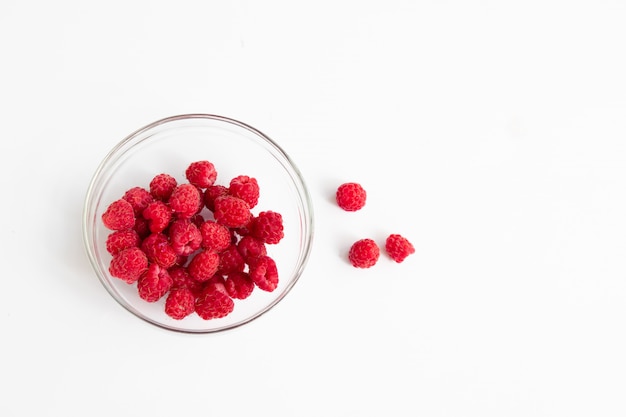 Red fresh raspberries in a glass bowl