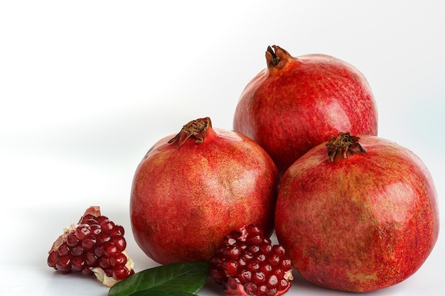 Red fresh and sweet pomegranate whole and in pieces isolated on white Side view closeup copy space selective focus