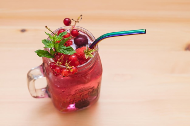 Red fruit water in glass jar with reusable metal straw Copy space