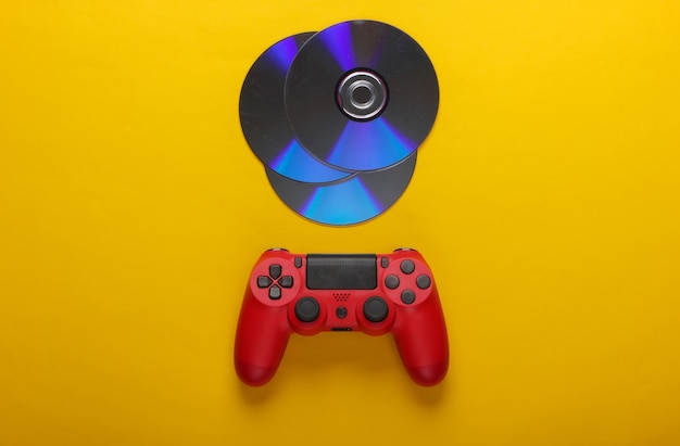 Red gamepad and cd compact discs on yellow