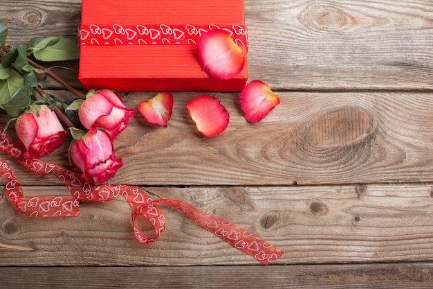 Red gift box and bouquet of roses on  wooden background