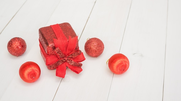 Red gift box and Christmas decoration on a white wooden table