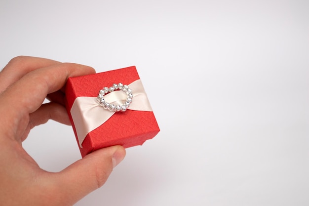 Red gift box in hand on white background.