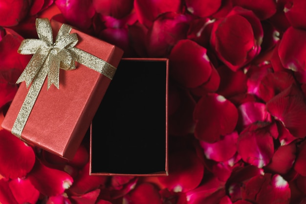 Фото Красная подарочная коробка на красных лепестках роз вид сверху, тема дня святого валентина