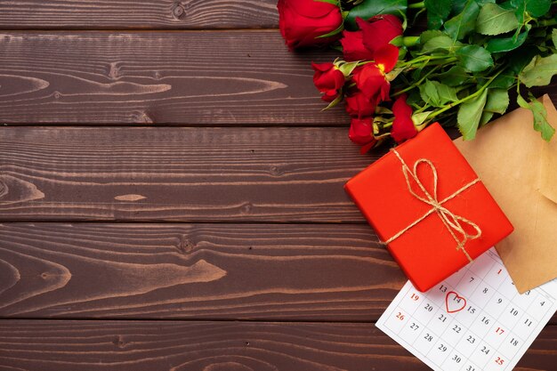 Red gift box and red roses on wooden top view