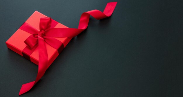Red gift box and ribbon on black background overhead black\
friday sale template