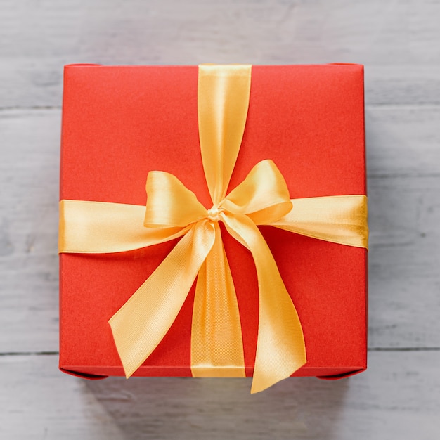 Red gift box tied with a golden ribbon. Ribbon tied with a bow on a box.