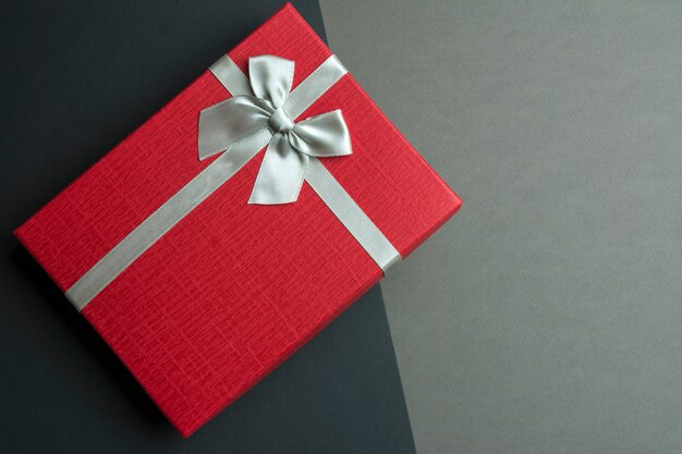 Red gift box with bow on black and grey background