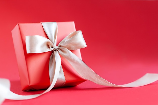 Red gift box with bow on red background Happy Birthday or Valentine's Day concept