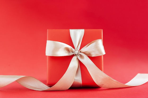 Red gift box with bow on red background Happy Birthday or Valentine's Day concept