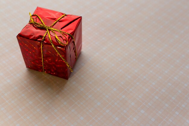 Red gift box with gold bow on pink background