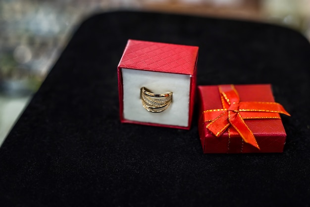 Red gift box with golden ring on black background