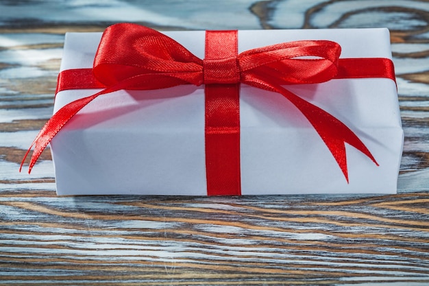 Red gift box with ribbon on wooden background