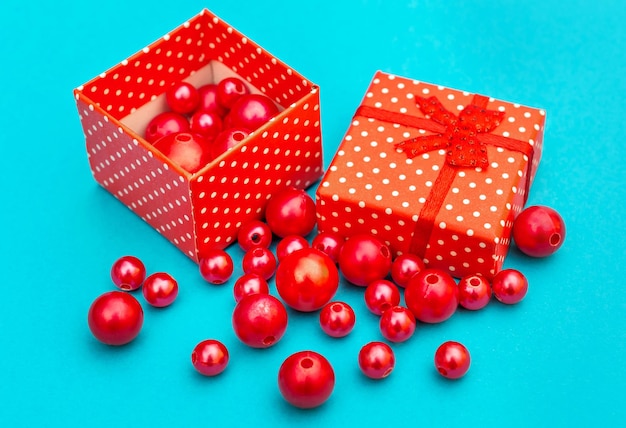 Red gift box with scattered red beads on blue background