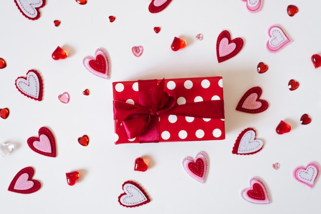 Red gift boxes peek out of a white paper bag with hearts