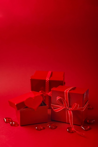 Scatole regalo rosse con nastro rosso e cuori decorativi su sfondo rosso