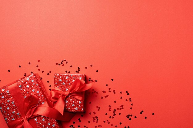 赤い固い背景でコピースペースで祝うバレンタインデーのリボン付きの赤いギフトボックス