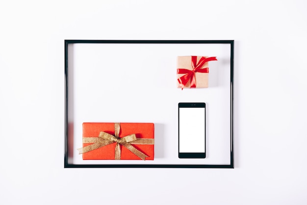 Red gift boxes with ribbons and mobile phone in a frame