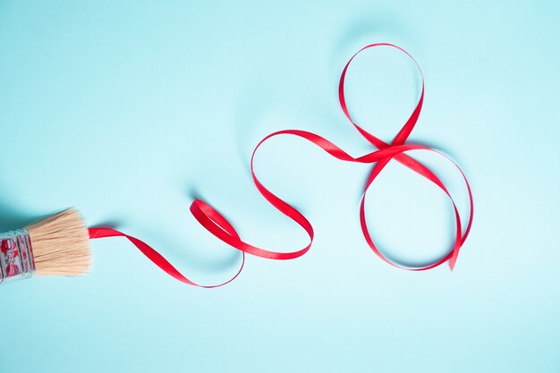 Red gift celebration ribbon in curved shape on blue background.