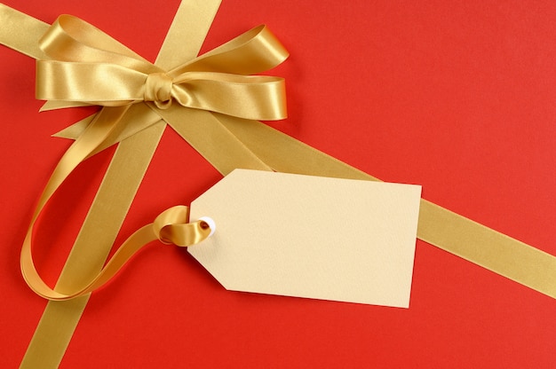 Red gift, gold ribbon bow, blank gift tag or label, copy space