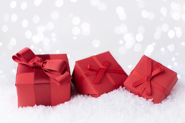 Photo red gifts in the snow with bokeh lights.