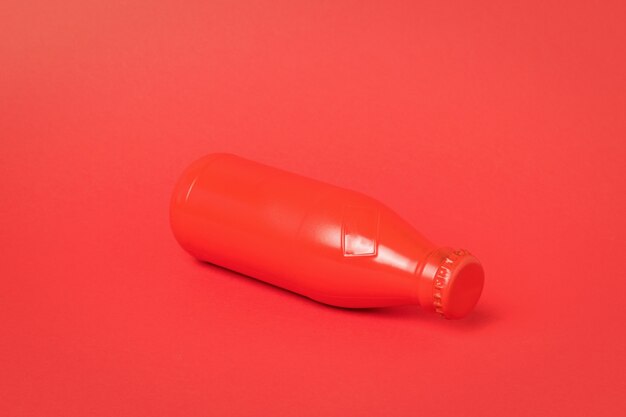 A red glass bottle lying on a red background. A container for refreshing drinks.