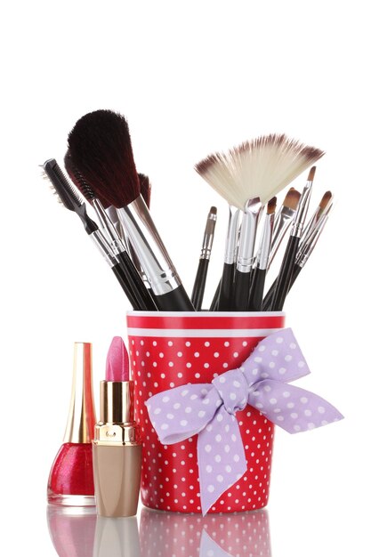 Red glass with brushes and cosmetics isolated on white