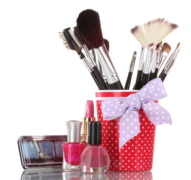 red glass with brushes and cosmetics isolated on white