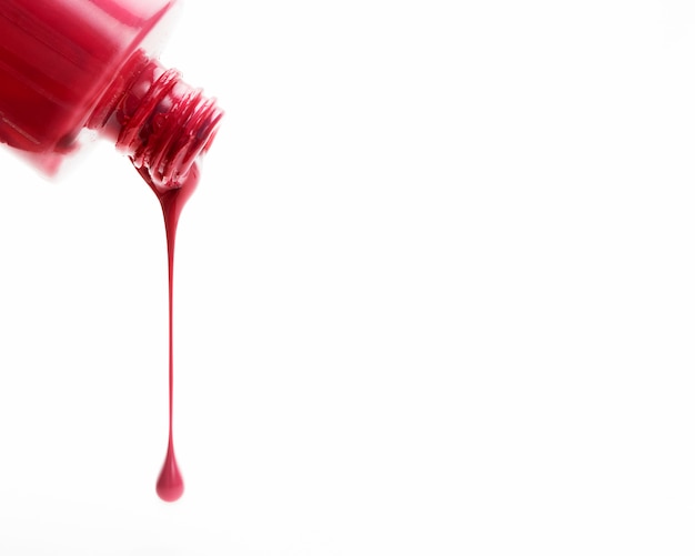 Photo red glossy nail polish pouring on the white background