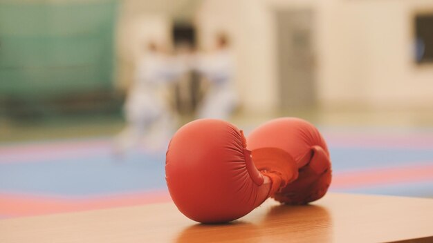 Guanti rossi per l'allenamento di karate su tatami durante l'allenamento, sfocato, primo piano