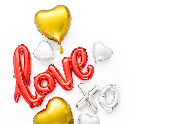 Red and gold  Foil Balloons in the shape of the word "Love" with hearts on white background. Love concept. Holiday, celebration. Valentine's Day or wedding/bachelorette party decoration.