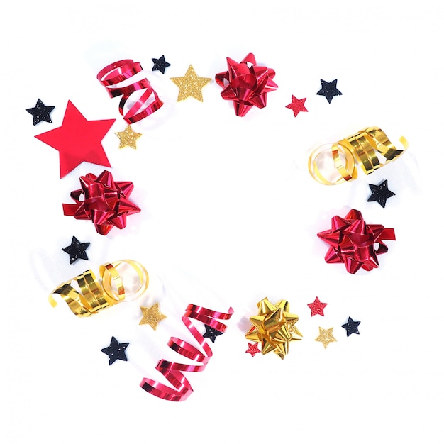 Red and gold holiday bows and serpentine, black, red and gold stars in a circle on a white background.

