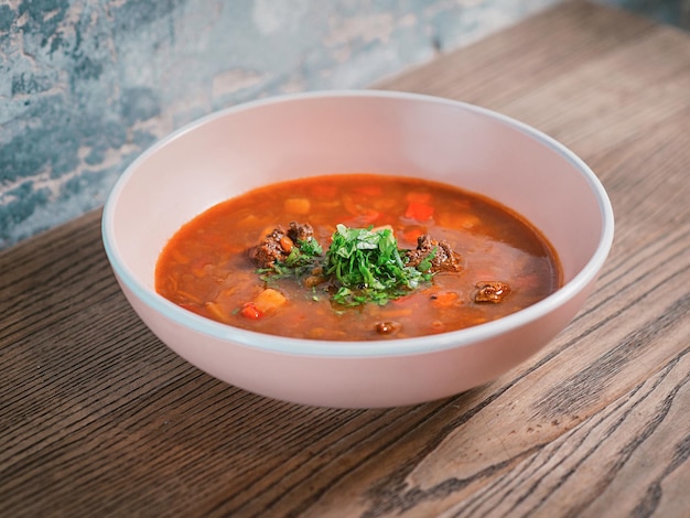 Photo red goulash or borscht in the plate on the table