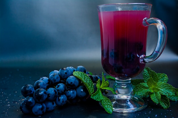 Red grape juice in glass and grape fruits