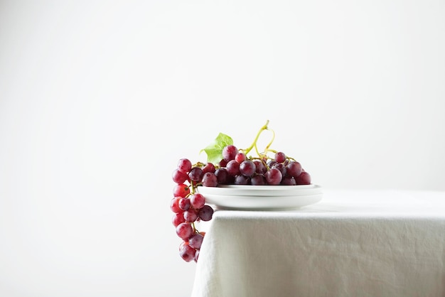 Red grape on the white linen tablecloth