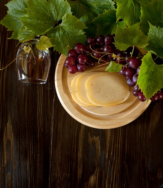 Uve rosse con foglie, bicchiere di vino e formaggio fresco. vista dall'alto, primo piano.