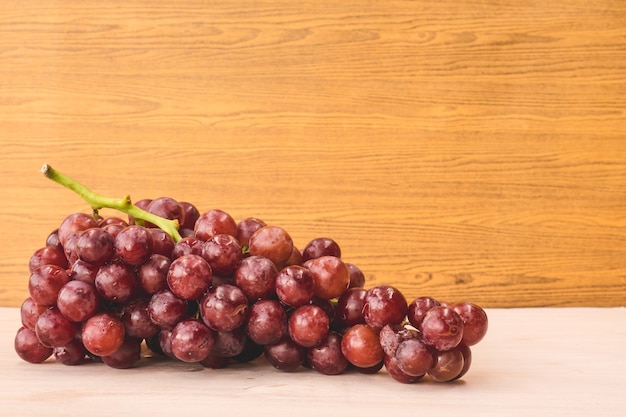 Red grapes on the wooden table. Free space for text