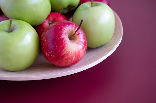 Photo red and green apples on a bamboo plate.