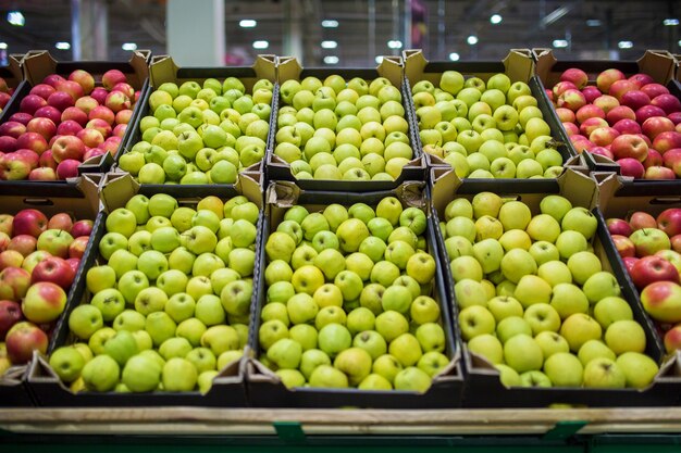 Mele rosse e verdi sul bancone del mercato. mele nelle scatole di cartone sullo scaffale della drogheria.