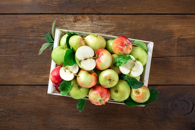 Red and green apples in wooden box on wooden table top view