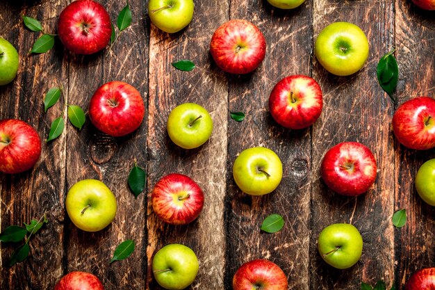 Red and green apples on wooden table.