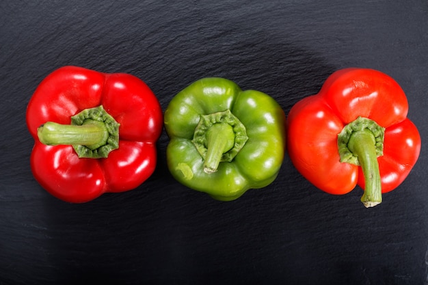 Red and green bell pepper on black slate stone plate with copy space