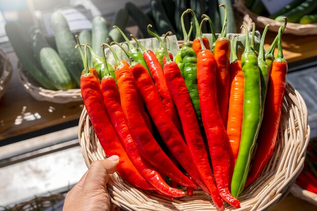 Photo red and green chili pepper in wooden basket in market