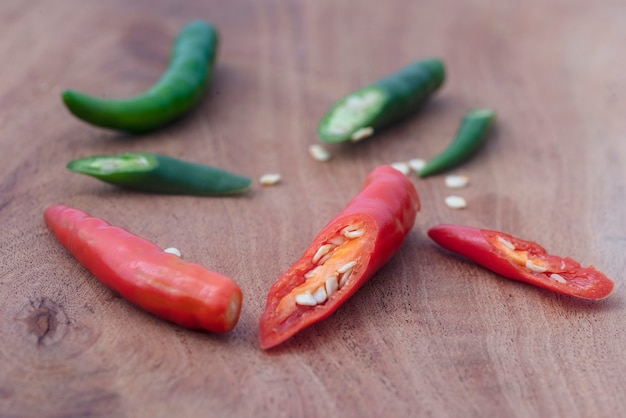 Peperoncini rossi e verdi disposti alternativamente su un tagliere di legno