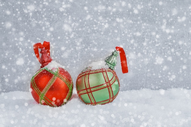 Red and green Christmas balls in snow. Christmas background. copyspace