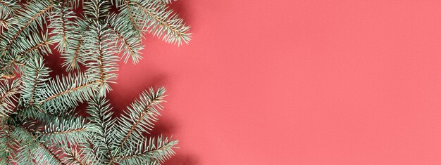 シンプルな装飾されていないモミの小枝と赤緑のクリスマスバナー。赤い紙にコピースペース。