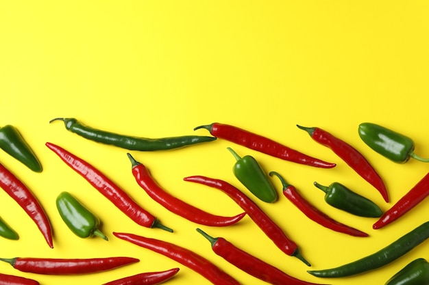 Red and green hot peppers on yellow background