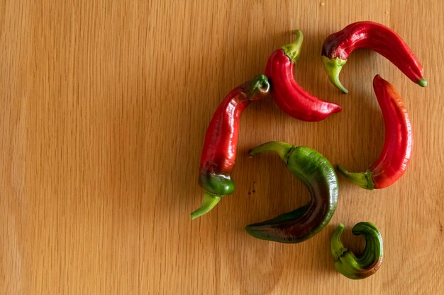 Photo red and green organic peppers on wood with copy space