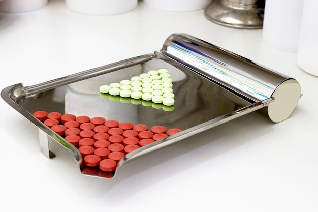 Red and green pills on counting tray on pharmacy counter