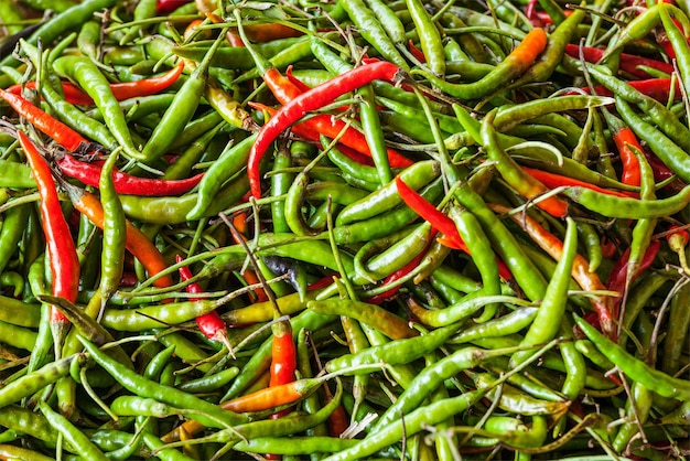 Red and green spicy chili peppers at asian market close up texture background